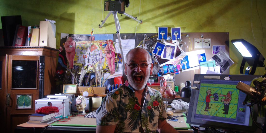 Friedel sits in his studio. Some of his artworks can be seen in the background.