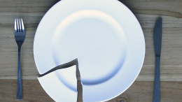 Ein leerer zerbrochener Teller auf einem Holztisch mit Messer und Gabel